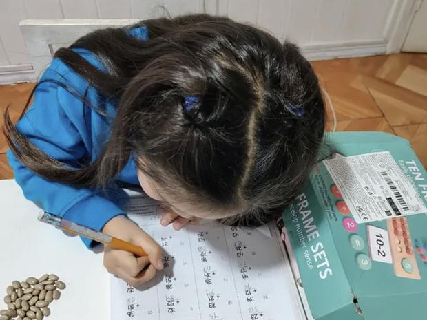Niña resolviendo sumas con apoyo de material concreto